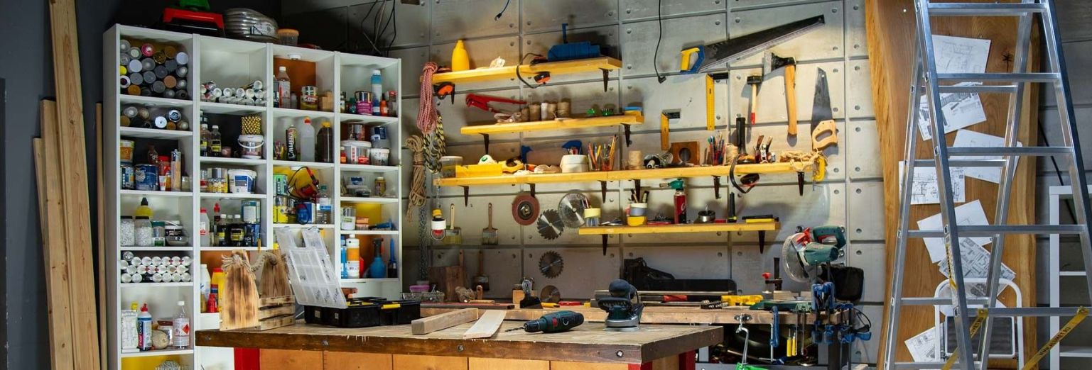 Garage work table with tools and equipment on shelves and hanging on the wall.