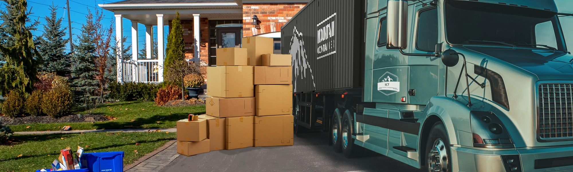 Branded shipping container on the back of a semi-truck in the driveway of a house with moving boxes on the ground next to the truck.