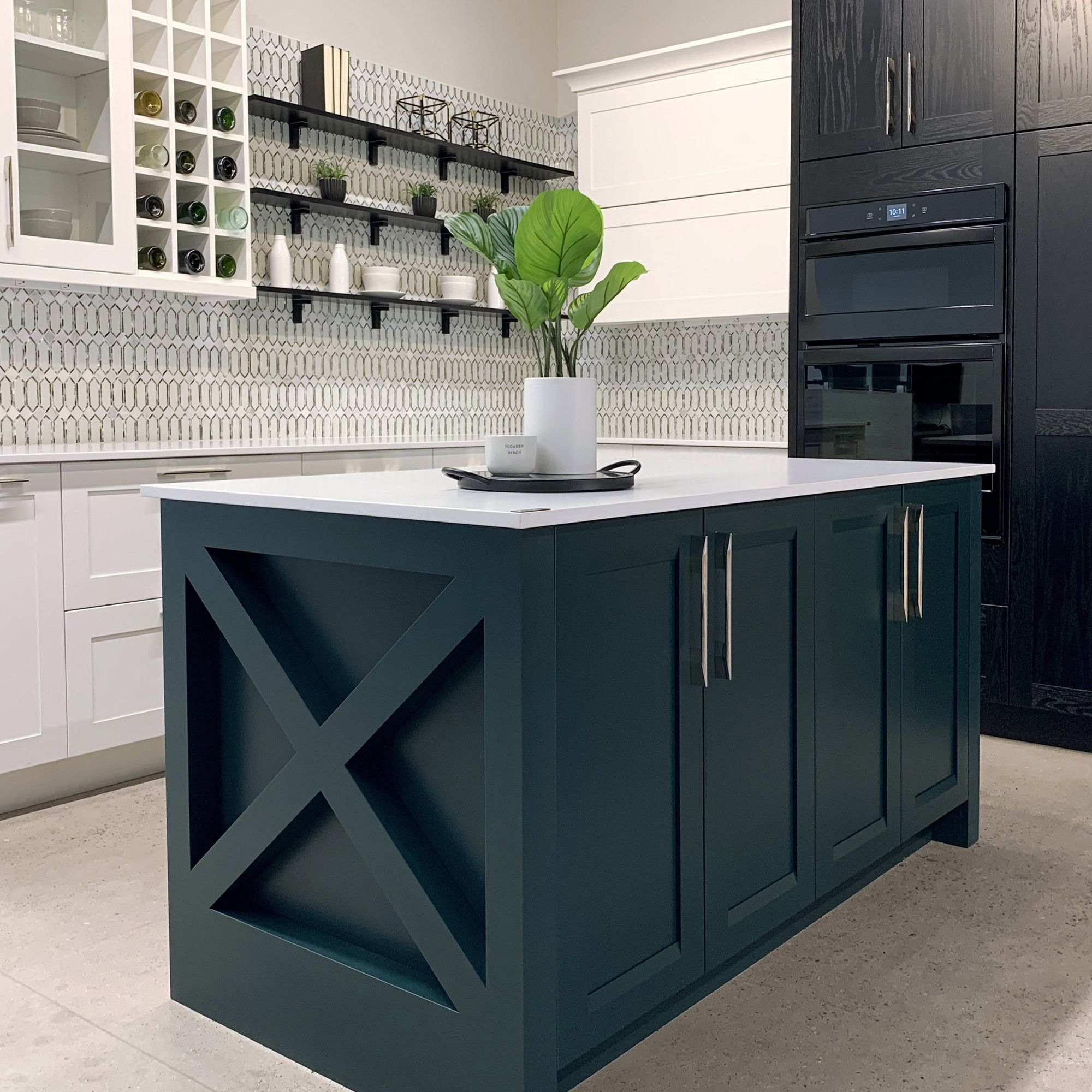Kitchen with teal island with white countertop. Cabinets are white with silver handles on the bottom and a mixture of open-faced black shelving and white glass-fronted cabinet on top with dished visible. Kitchen with teal island with white countertop. Cabinets are white with silver handles on the bottom and a mixture of open-faced black shelving and white glass-fronted cabinet on top with dished visible.