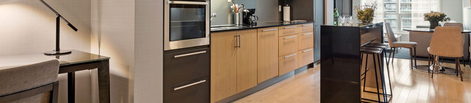 Closeup image of a nicely renovated kitchen and living room with wood cabinets and black countertops