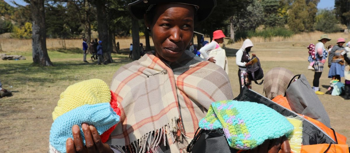 Mother in Tuke, Lesotho holds up warm woolen donations received from World Vision's Gift-in-Kind Program