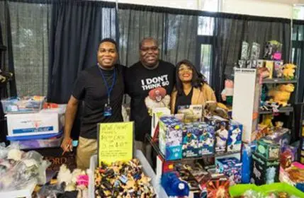 Group of three behind a booth selling products at Kingcon in the vendor hall
