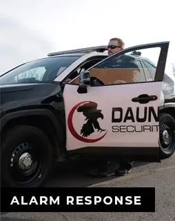 Alarm Response, Close image of a patrol vehicle with the dauntless logo on the door with a patrol officer standing behind the open door.