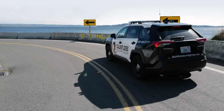 Security Vehicle patrolling a curving roadway overlooking puget sound.