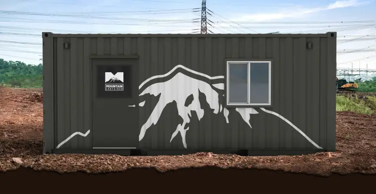 Grey branded shipping container with a door and window sitting on the dirt ground at a construction site.