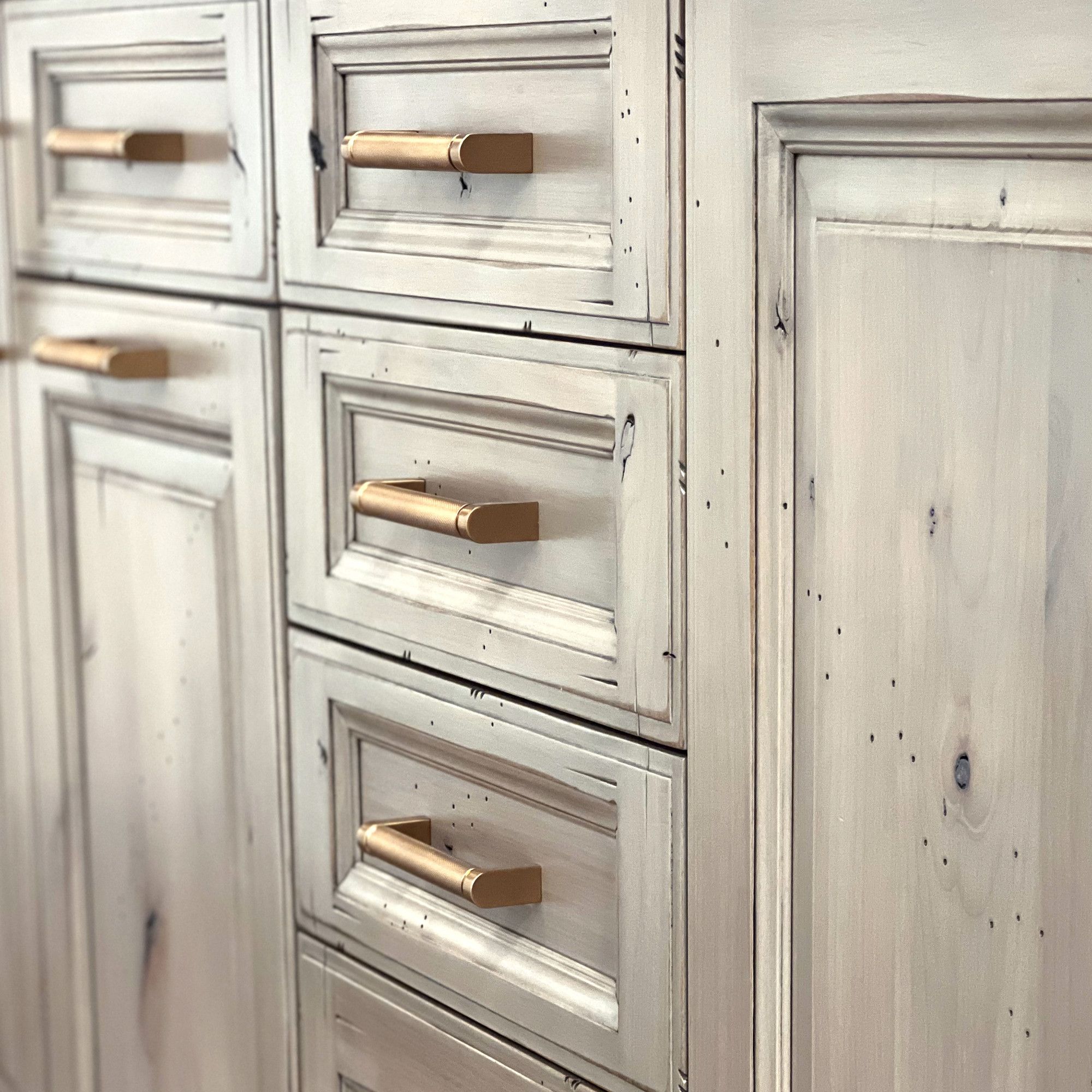 Close up of cabinets and drawers made from white colored wood with copper handles