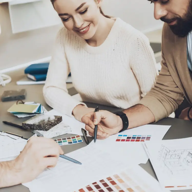 Couple sitting at a table while happily looking through color samples and pointing at favorites. 