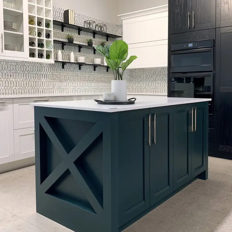 Kitchen with teal island with white countertop. Cabinets are white with silver handles on the bottom and a mixture of open-faced black shelving and white glass-fronted cabinet on top with dished visible.