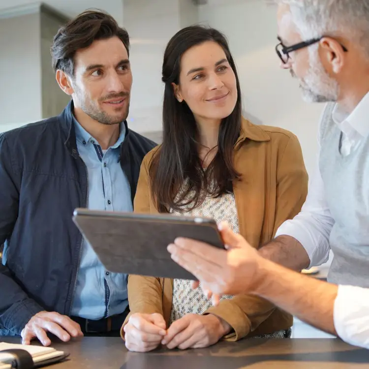 Happy couple talking with consultant who is holding a tablet and explaining something