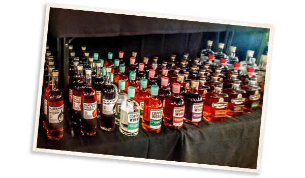 Bottles of Hard Alcohol lined up on a table with a black table cloth