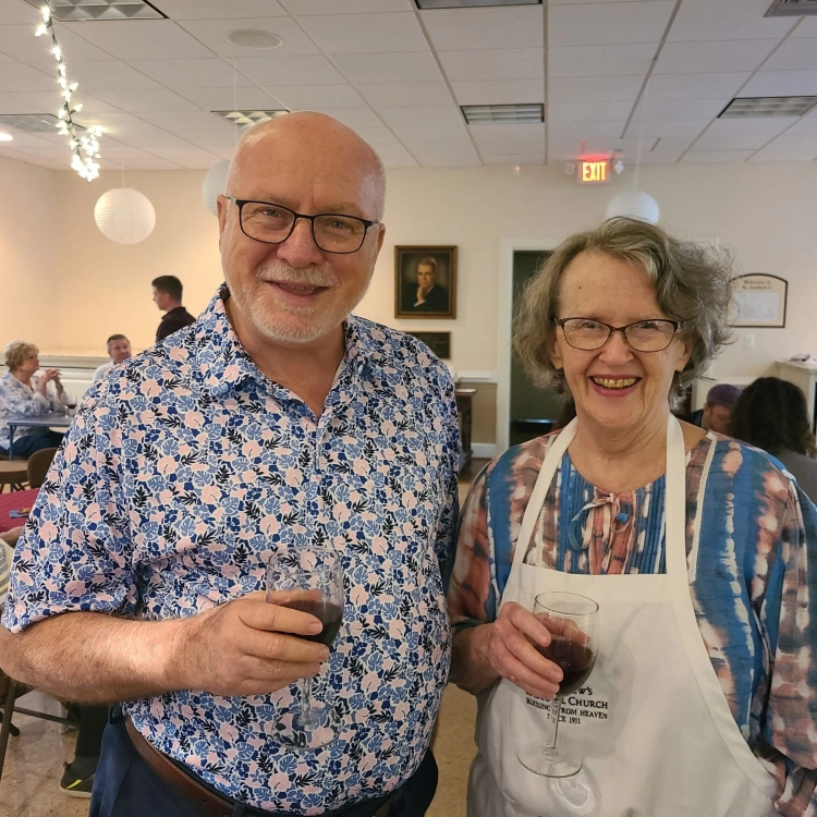 Two church members smile together at a reception held in the church social hall.